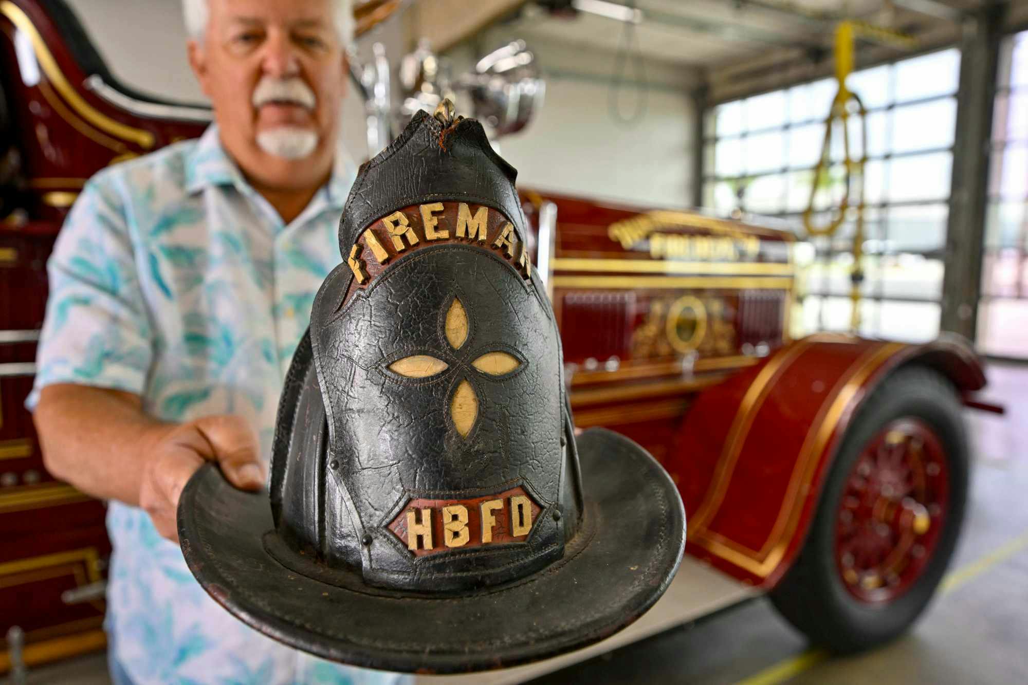 Terry Hibler shows off a 100-year-old helmet worn by his grandfather, a volunteer Huntington Beach firefighter.