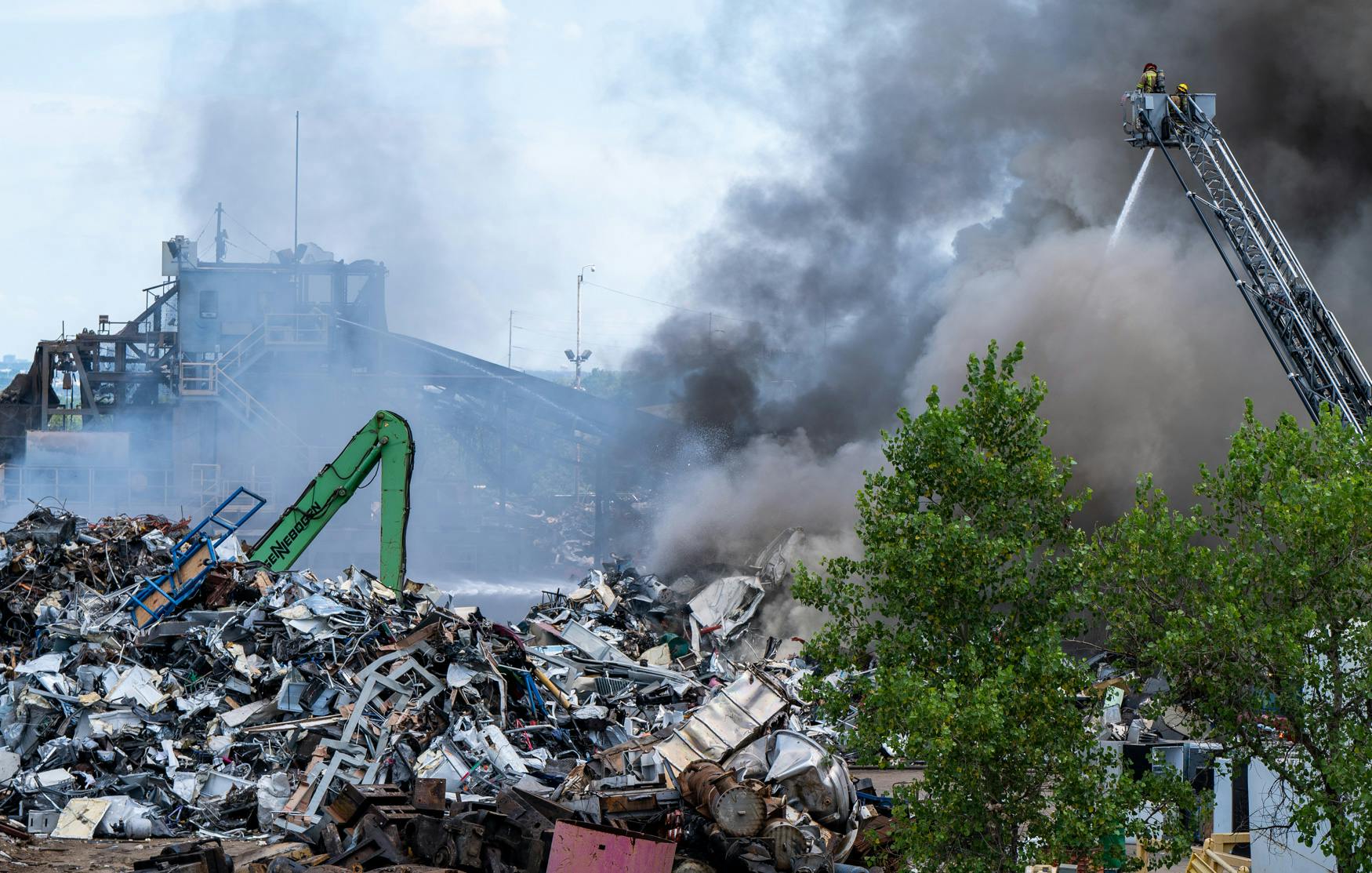 Smoke dwarfs an aerial platform as flames engulfed a large pile of products awaiting recycling.