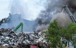 Smoke dwarfs an aerial platform as flames engulfed a large pile of products awaiting recycling. Smoke dwarfs an aerial platform as flames engulfed a large pile of products awaiting recycling.