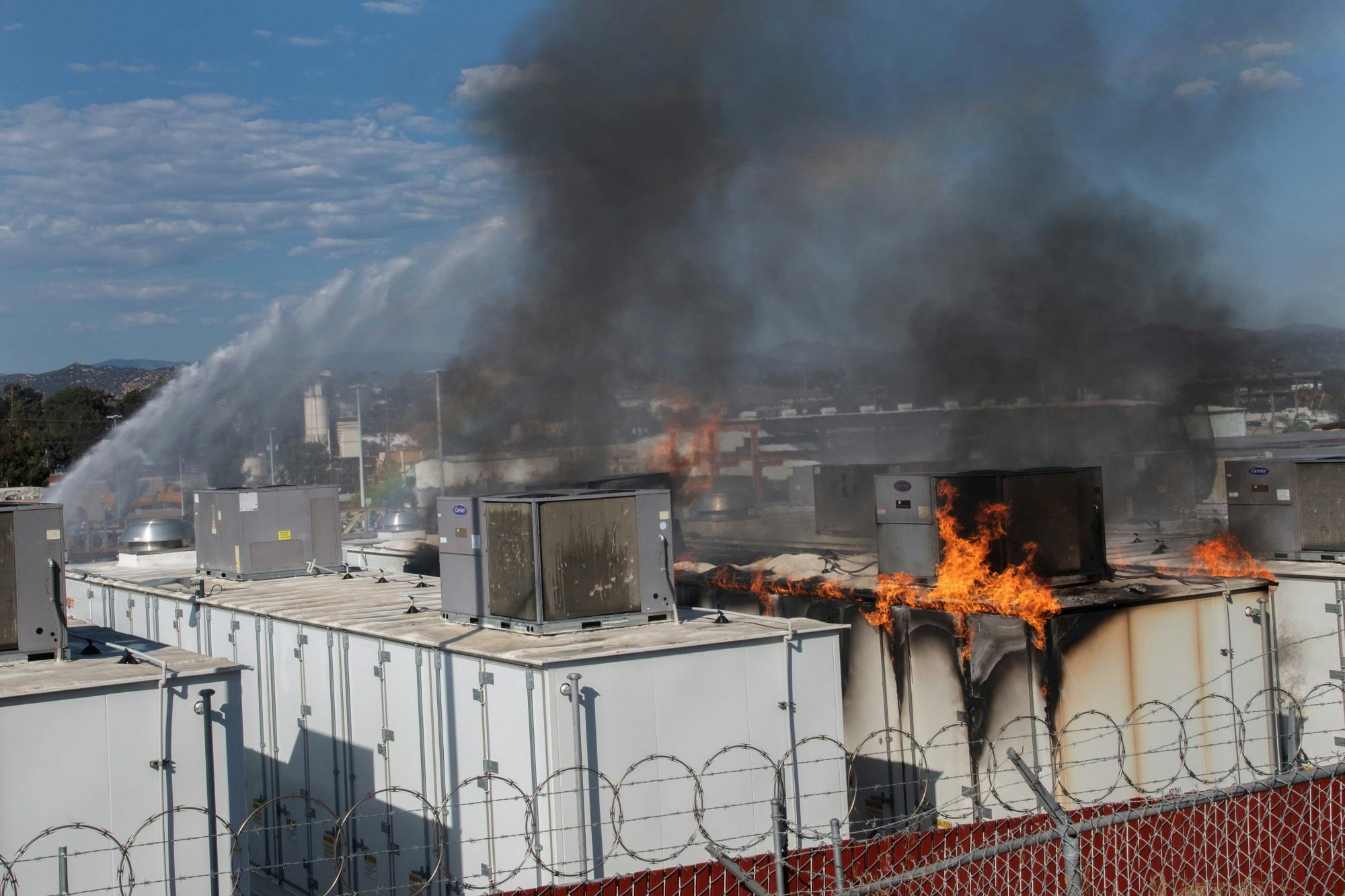 Firefighters apply water as fire burns through a lithium battery storage container at the San Diego Gas and Electric N.E. Operations Center in Escondido.