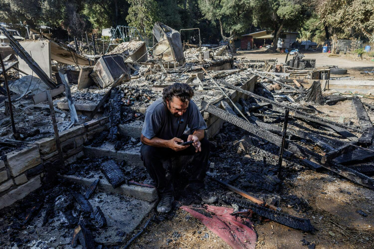 Garrett Keene sits on the front steps of his home that was destroyed in the Airport fire in El Cariso Village on Sept. 12 in Lake Elsinore, California.