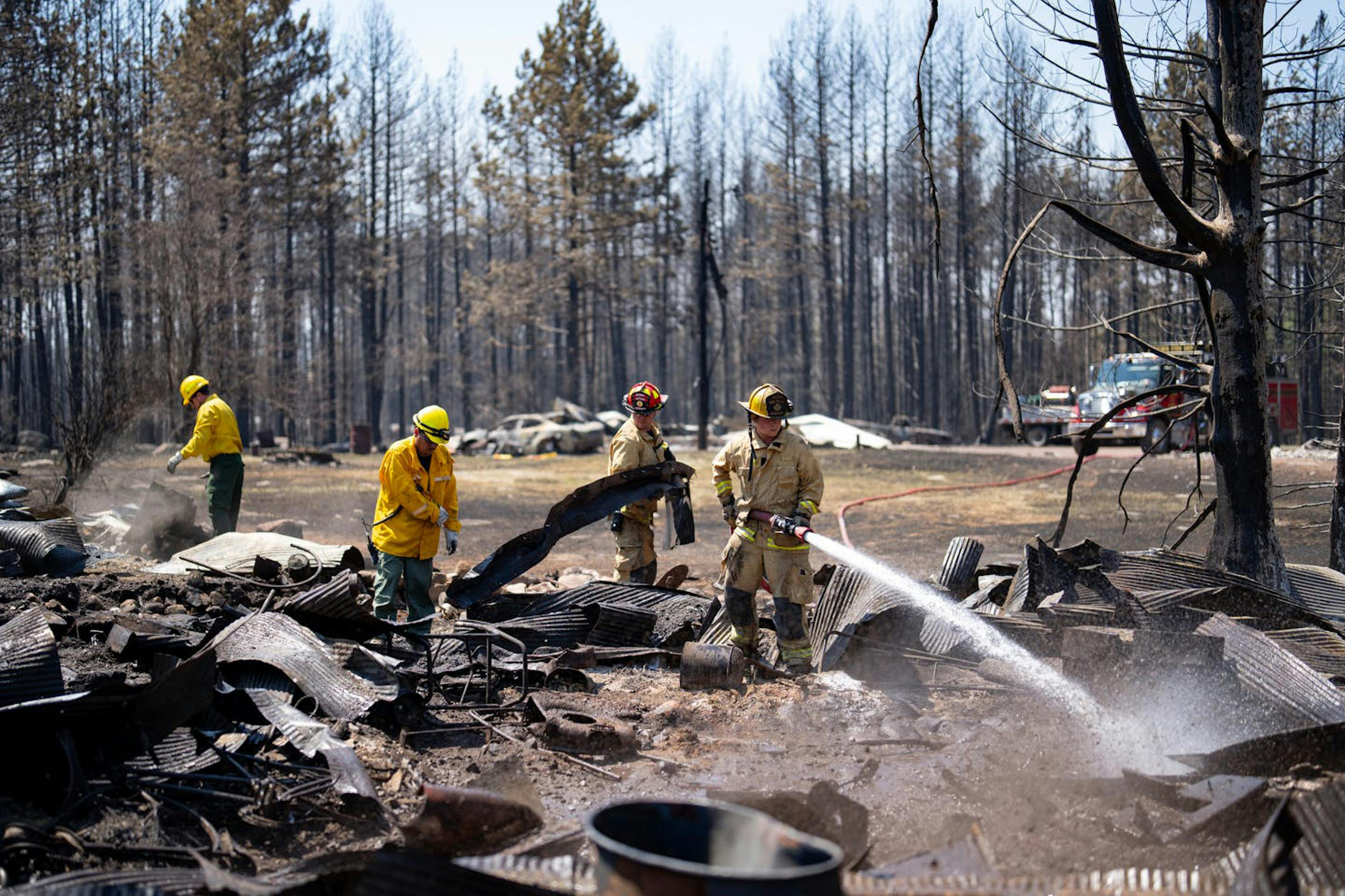 Firefighters Joshua Donahue, Chris Schlosser, Jon Settergren and Michael Hemmerich, left to right, move debris as they combat the Camp House wildfire in Brimson, MN last month.