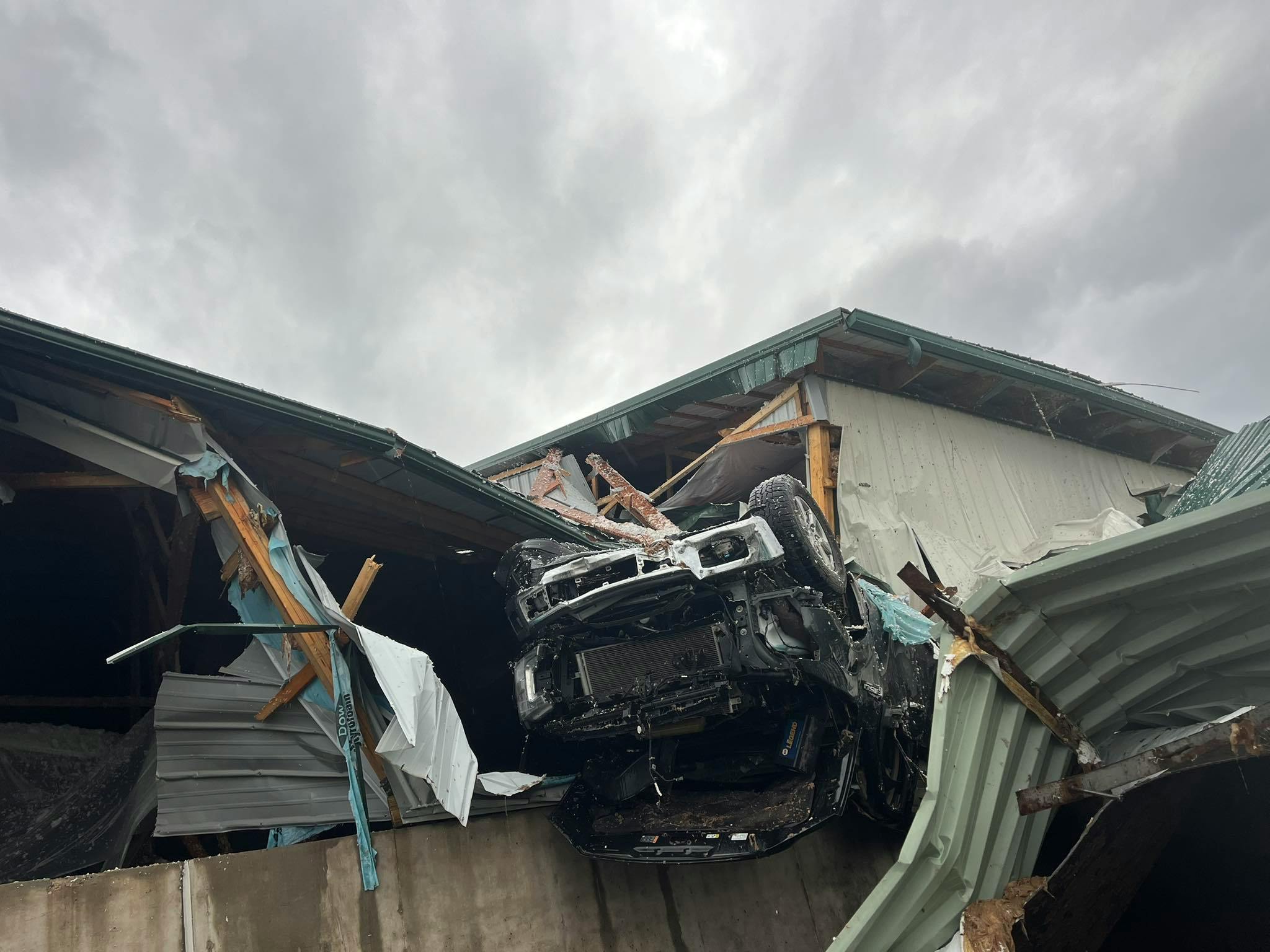 A truck was left in the roof debris of a collapsed building.