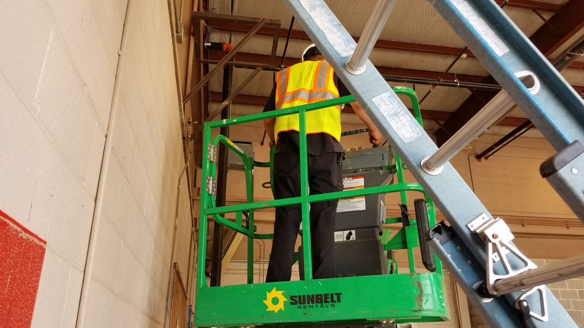 Alarm tech with SAFE Solutions installing cable for an access control system in a steel building. The lift makes the job both safer and faster.