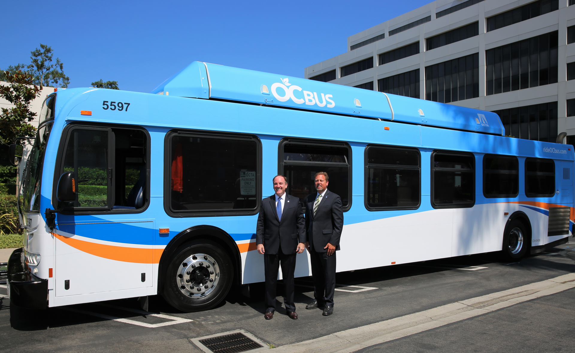 OCTA Chairman Jeff Lalloway, also Irvine&rsquo;s mayor pro tem, (left) and OCTA CEO Darrell Johnson stand in front of the redesigned OCTA bus, which will soon roll out on Orange County streets.