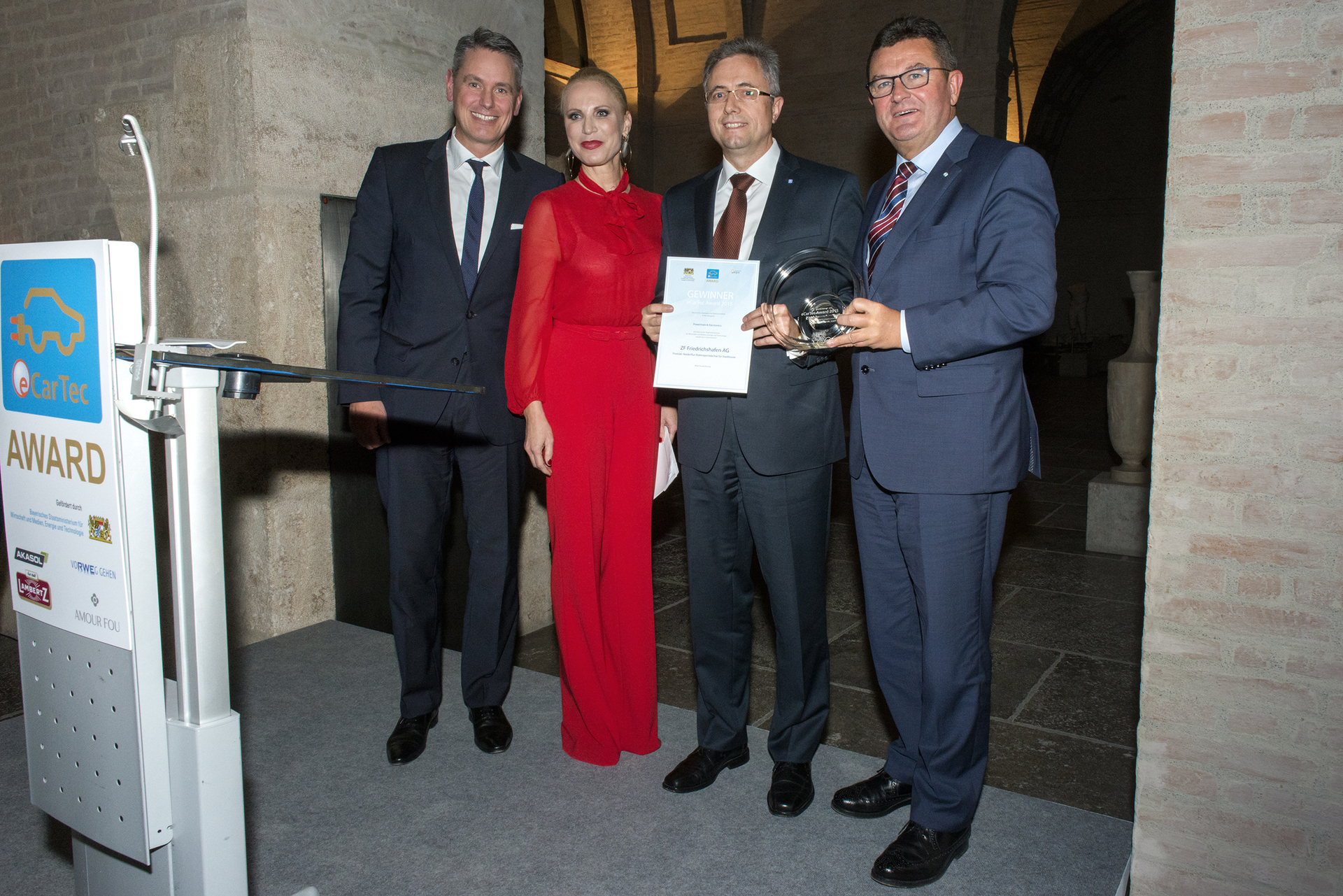 Festive presentation of the Bavarian State Award for Electric and Hybrid Mobility to ZF in Munich. From left to right, Robert Metzger, Managing Director MunichExpo Veranstaltungs GmbH, opera star and award show presenter Nadja Michael, Werner Hechberger, Senior Sales Manager for Axle and Transmission Systems for Buses and Coaches at ZF and Franz Josef Pschierer, State Secretary in the Bavarian Ministry of Economic Affairs and Media, Energy and Technology.