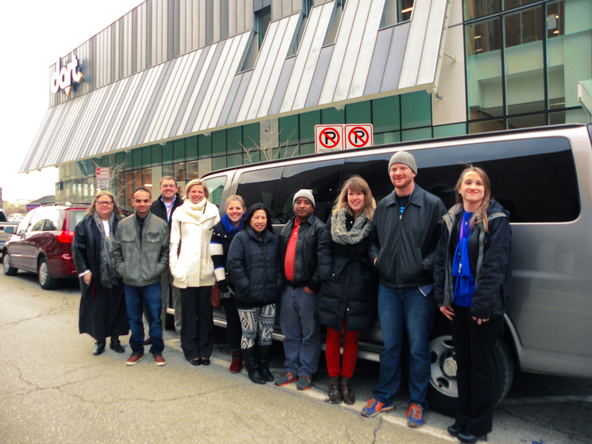 Representatives from Central Iowa Shelter & Services, U.S. Committee for Refugees and Immigrants, ArtForceIowa and DART stand in front of one of the donated RideShare vans.