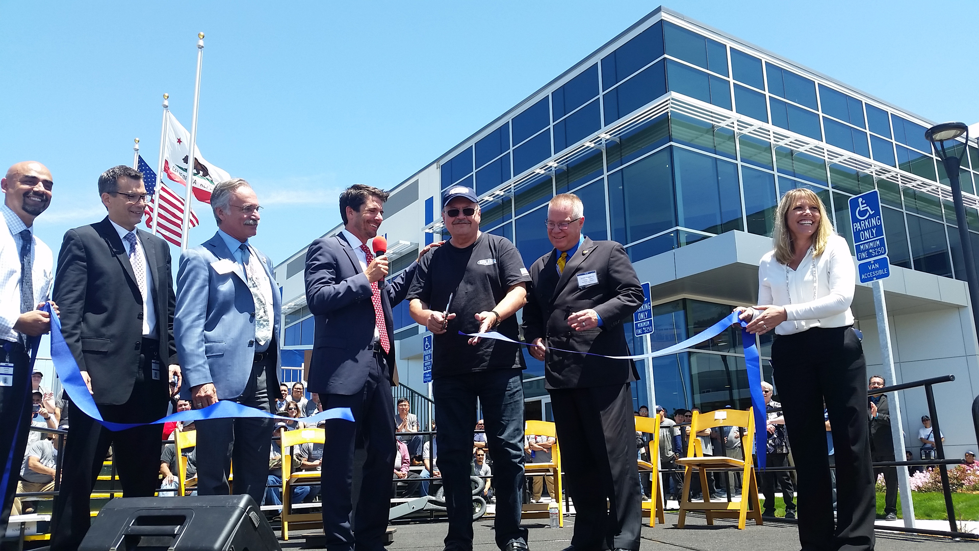 Most-tenured Gillig employee Stanley Alcon, with 50 years of service, cuts the ribbon.