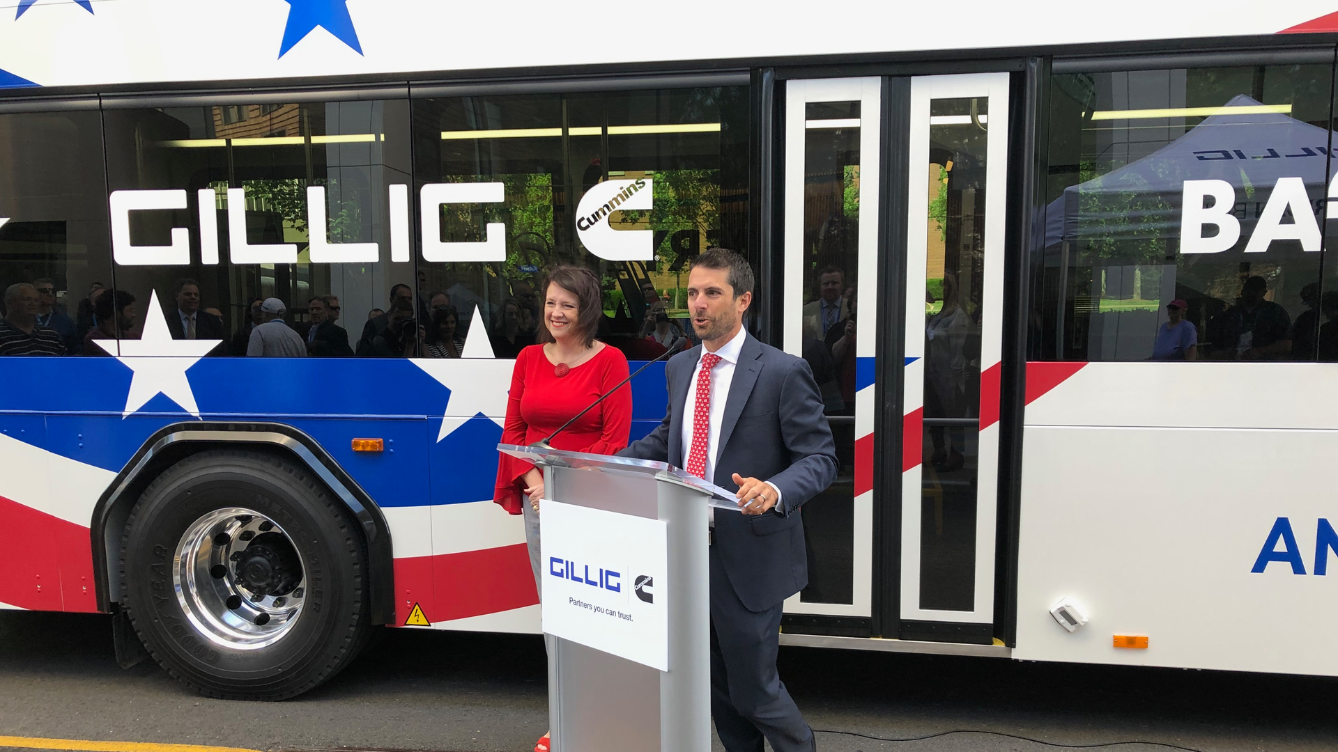 Cummins Vice President-Electrified Power Julie Furber. left, and GILLIG President and CEO Derek Maunus speak to a crowd at the APTA 2019 Mobility Conference in front of GILLIG's new battery electric bus.