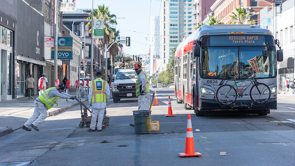 Paint shop crew removing old pavement markings for installation of temporary emergency transit only lanes.