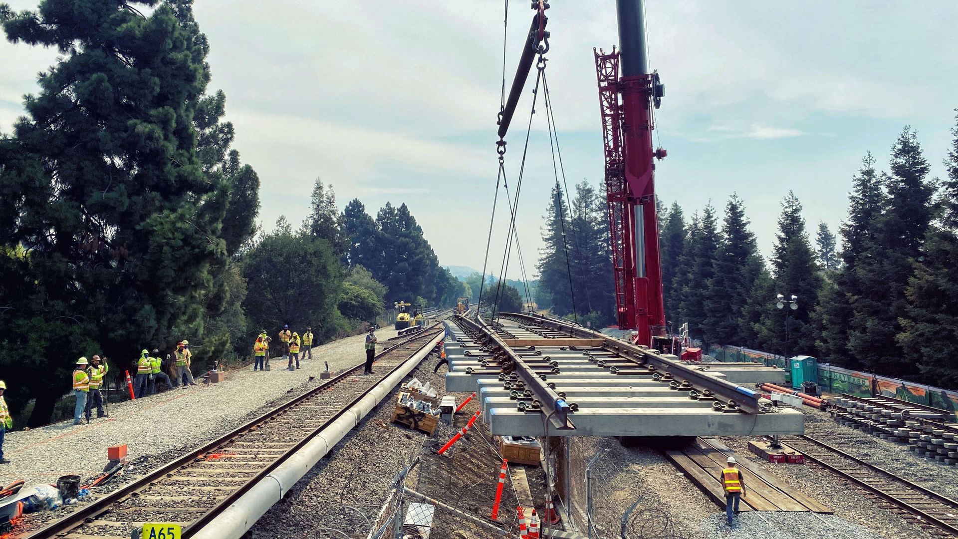 A track panel is moved via crane to its spot within the right of way.