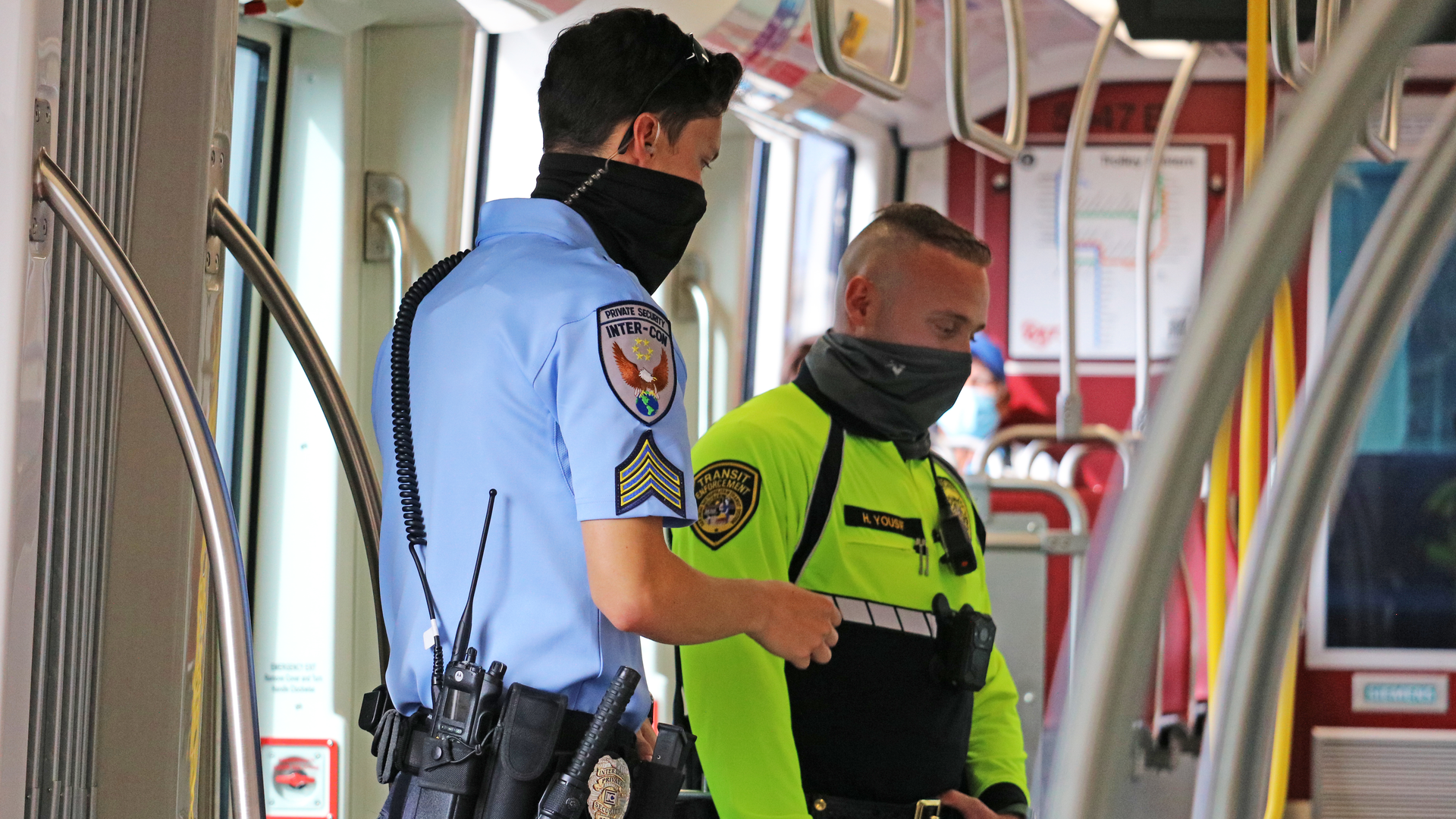 An MTS transit security officer in bright yellow and an Inter-Con security contract officer in blue on a joint patrol.