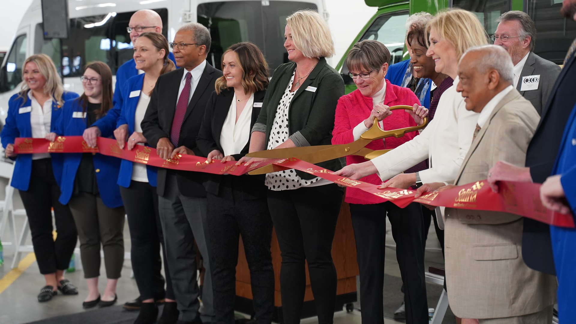 Kansas Gov. Laura Kelly, center right with scissors, with FTA Administrator Nuria Fernandez, celebrates the opening of OCCK, Inc., Transportation's expanded facility in Salina and announced the awarding of more than $13 million in transit grants through the AIC Public Transit Program.