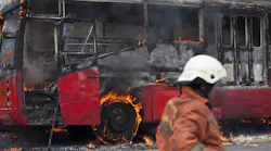 A bus burning from a fire with fire department on site. A bus burning from a fire with fire department on site.