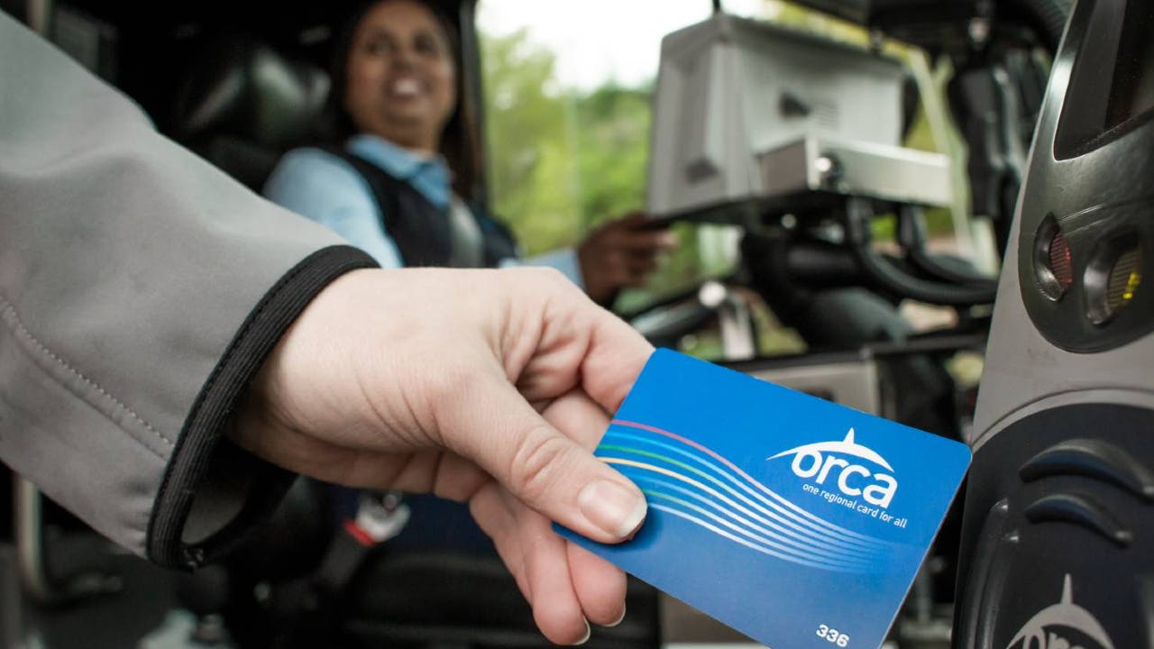 A woman hand-swiping an ORCA LIFT card.