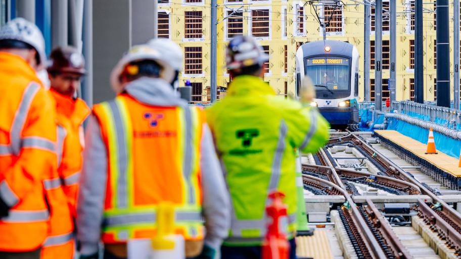 Sound Transit employees greet an approaching test train operator during a station tour in March 2024.