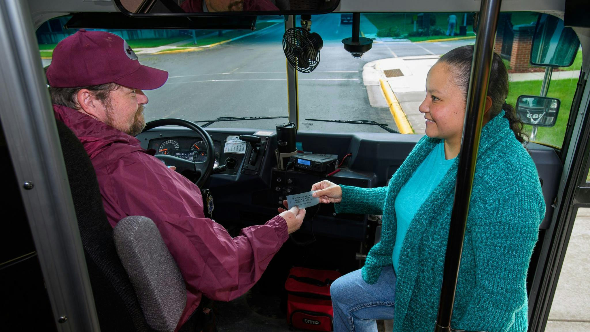 An Arrowhead Transit bus operator talking to a passenger on the steps of a bus.