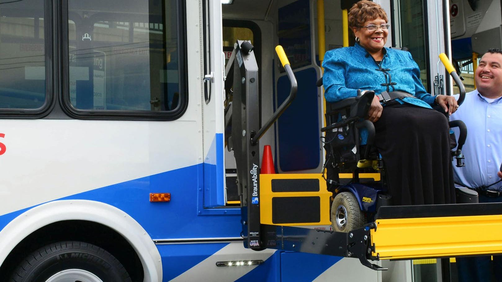 SamTrans paratransit bus operator and a rider in a wheelchair on a bus ramp.