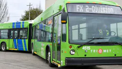 A green 60-foot TriMet bus drives down a street A green 60-foot TriMet bus drives down a street
