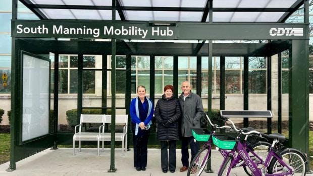 three people stand outside of manning blvd mobility hub entrance