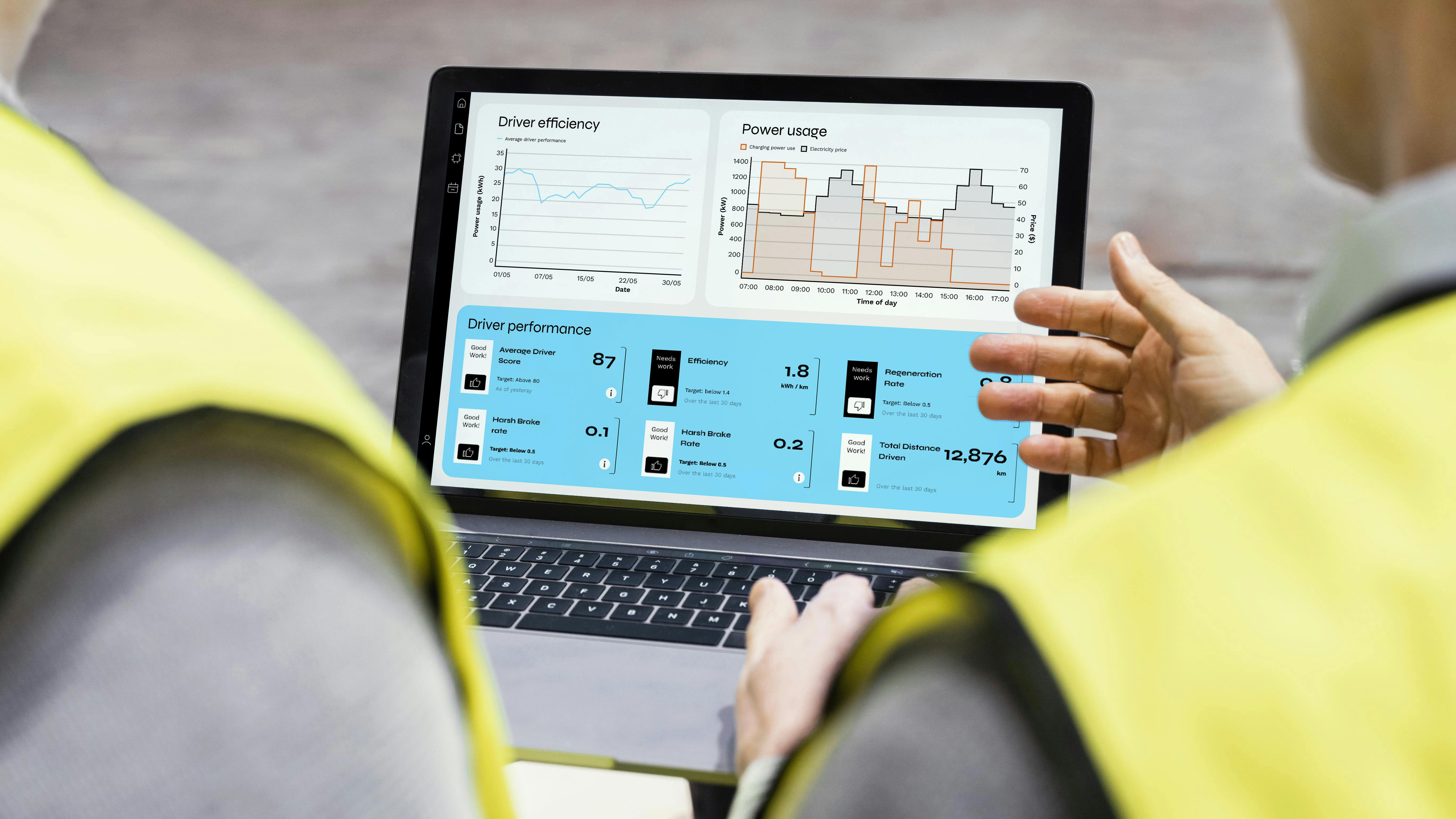 two people stand with backs to camera looking at laptop screen with charts