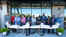Line of people stand outside apartment building cutting ribbon Line of people stand outside apartment building cutting ribbon