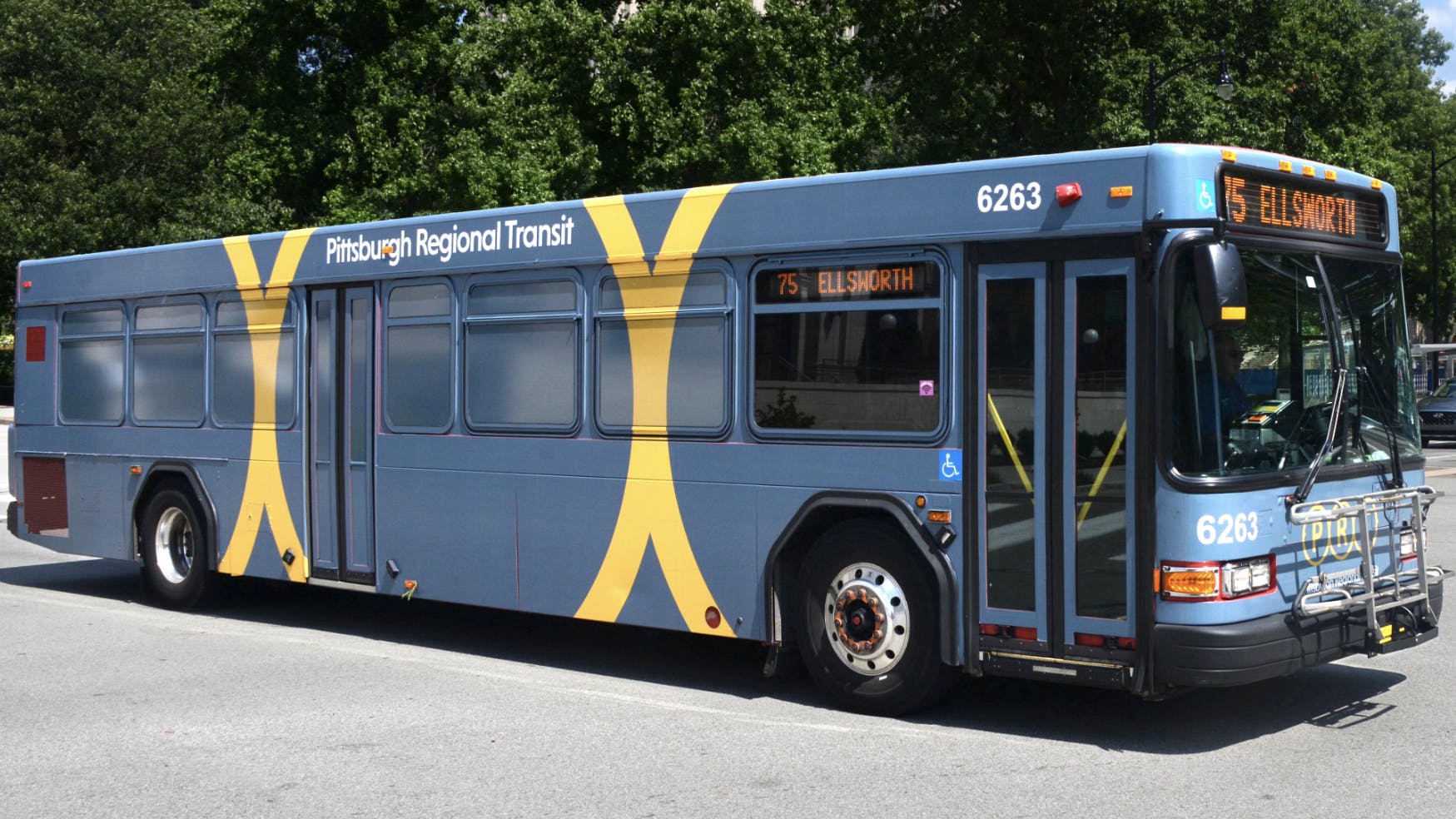 PRT grey bus drives down the street on sunny day