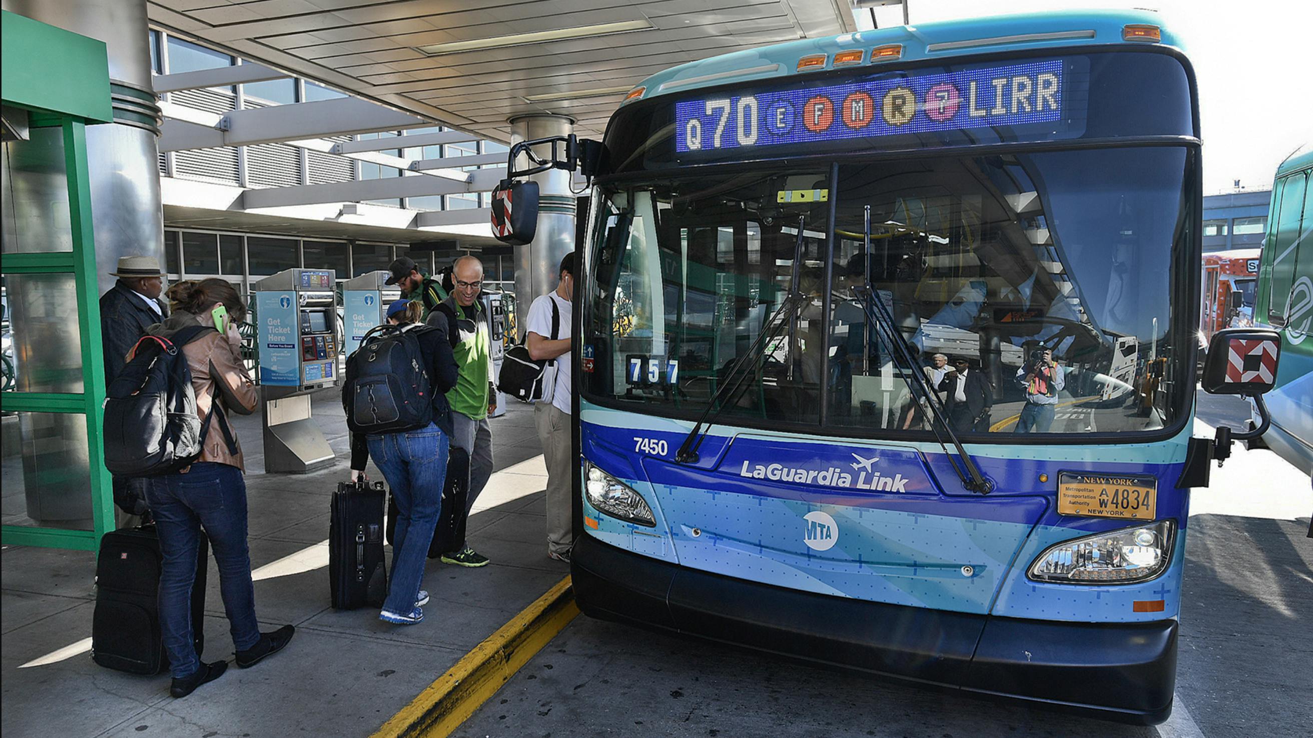 MTA Q70 blue bus waits outside terminal at LaGuardia for passengers to board