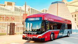 a red MAX-branded pulls out in front of a building in downtown a red MAX-branded pulls out in front of a building in downtown