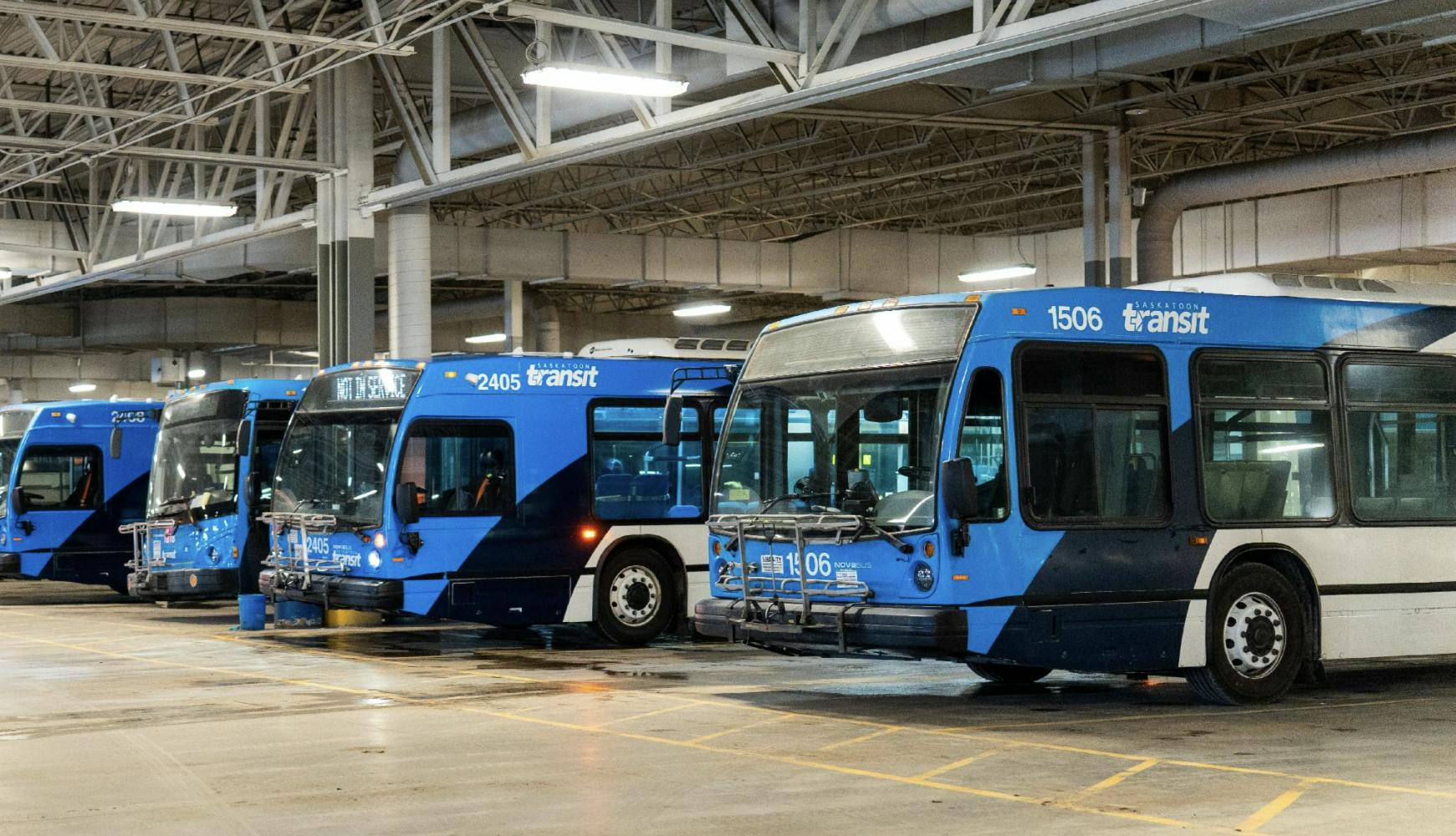 a row of saskatoon transit-branded buses parked in bus garage