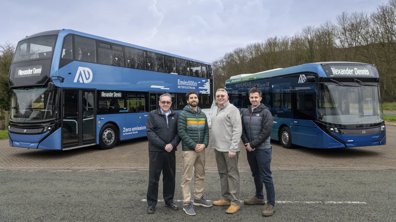 four men pose in front of a blue double decker and 40 foot alexander dennis buses