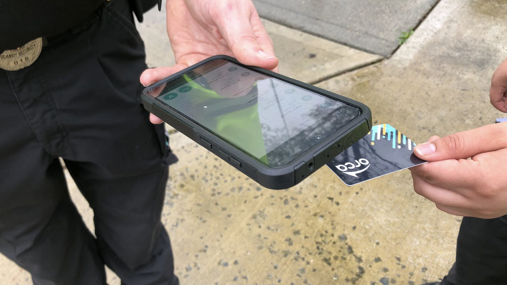 person taps their orca card with a fare enforcement officer's validator