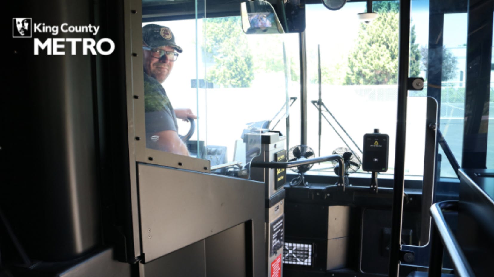 bus operator sits in bus behind a safety partition