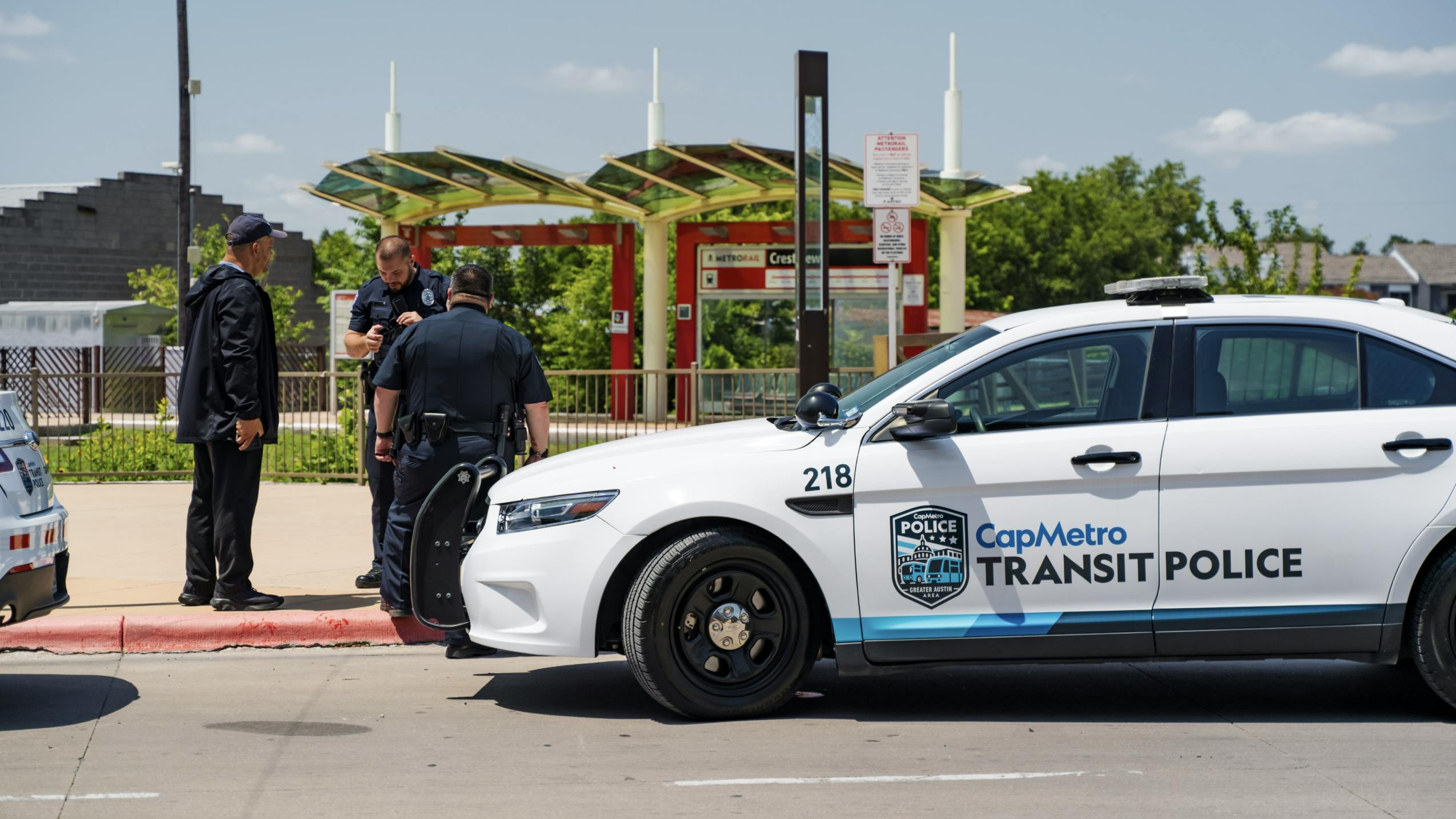 three patrol officers stand in front of capmetro transit police branded SUV