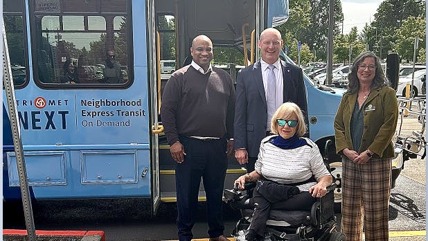 Gresham Mayor Travis Stovall; TriMet Executive Director of Public Affairs, JC Vannatta; TriMet Committee on Accessible Transportation (CAT) Chair, Jan Campbell; and Chief People and Strategy Officer for Meals on Wheels People, Jessica Morris, with a TriMet NEXT bus at the Multnomah County East Building in Gresham.
