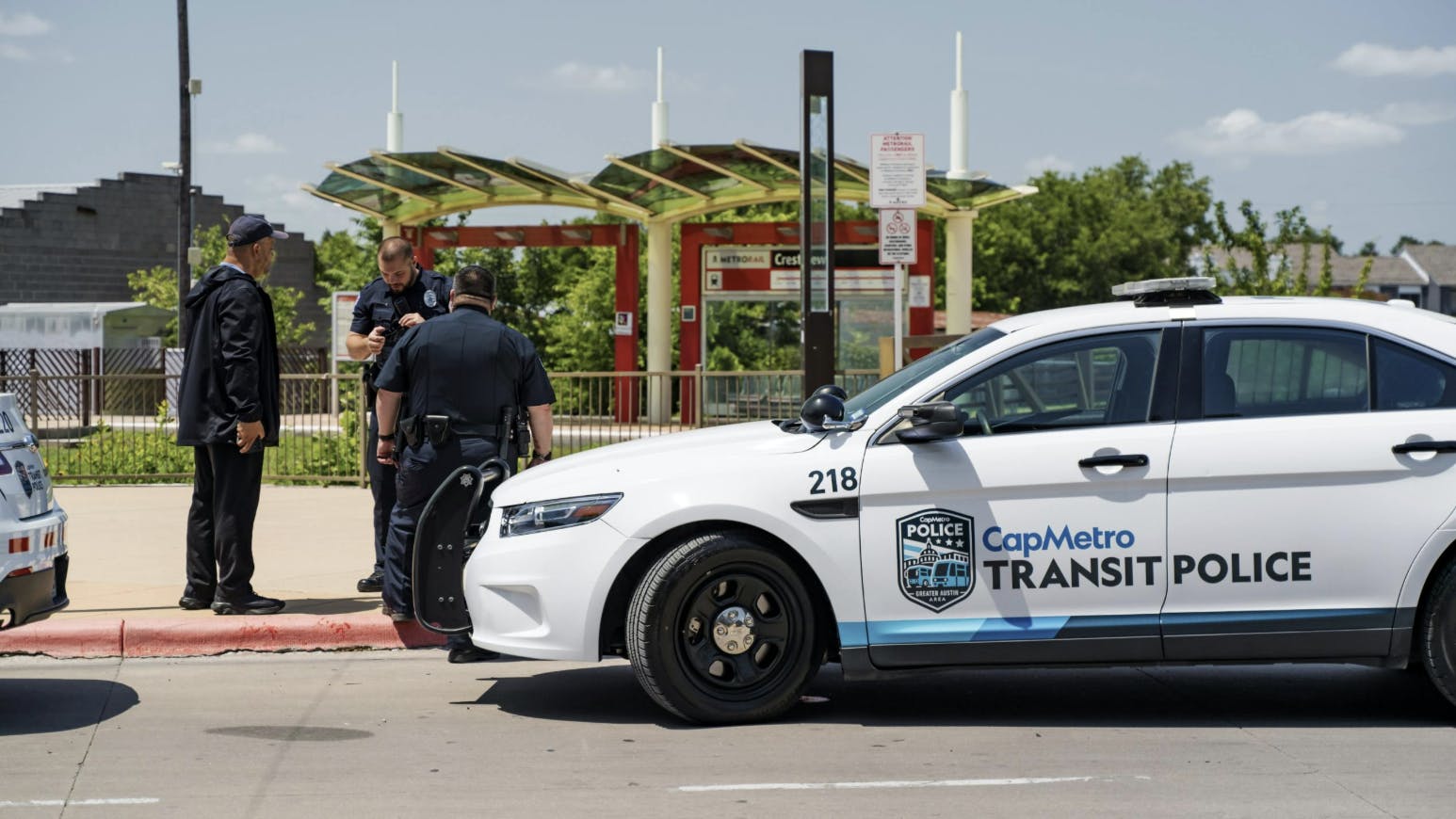 three transit police officers stand outside in front of a CapMetro transit police SUV