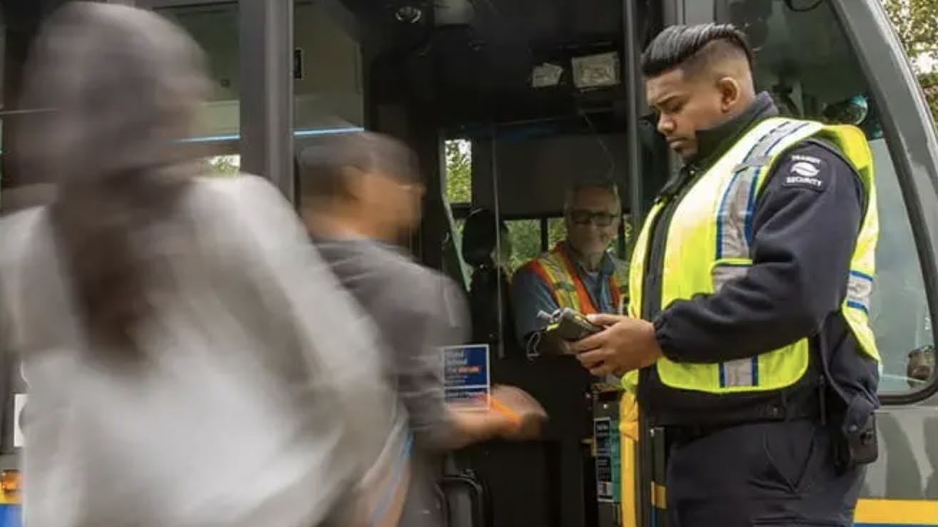 fare inspector stands in front of a bus checking passengers' fares before they board