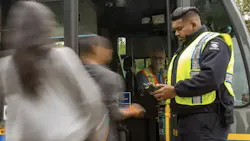fare inspector stands in front of a bus checking passengers' fares before they board fare inspector stands in front of a bus checking passengers' fares before they board