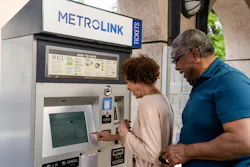 a man and a woman stand in front of a Metrolink ticket vending machine to purchase a ticket a man and a woman stand in front of a Metrolink ticket vending machine to purchase a ticket