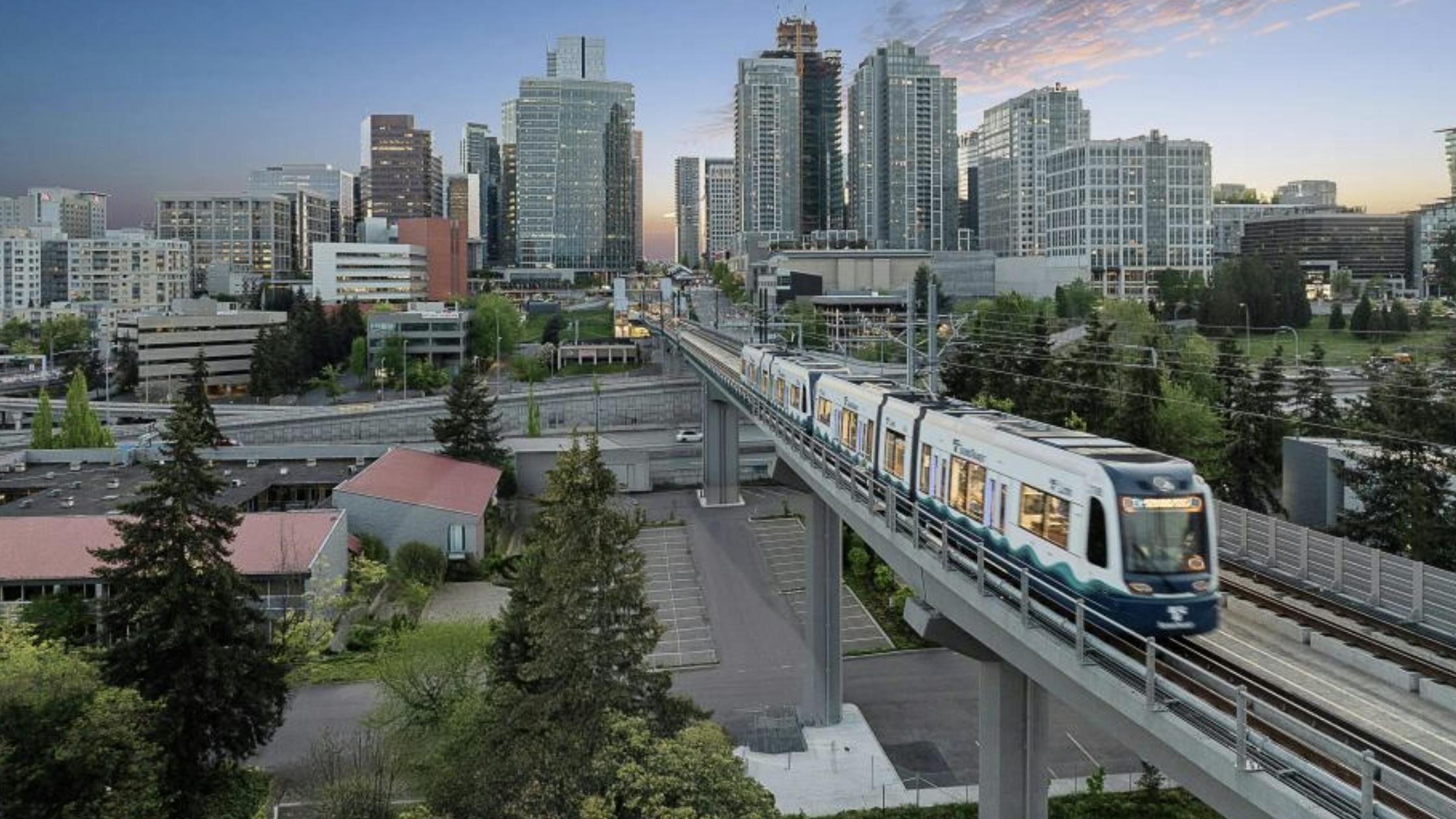 a sound transit train runs on elevated guideway with city skyline in background