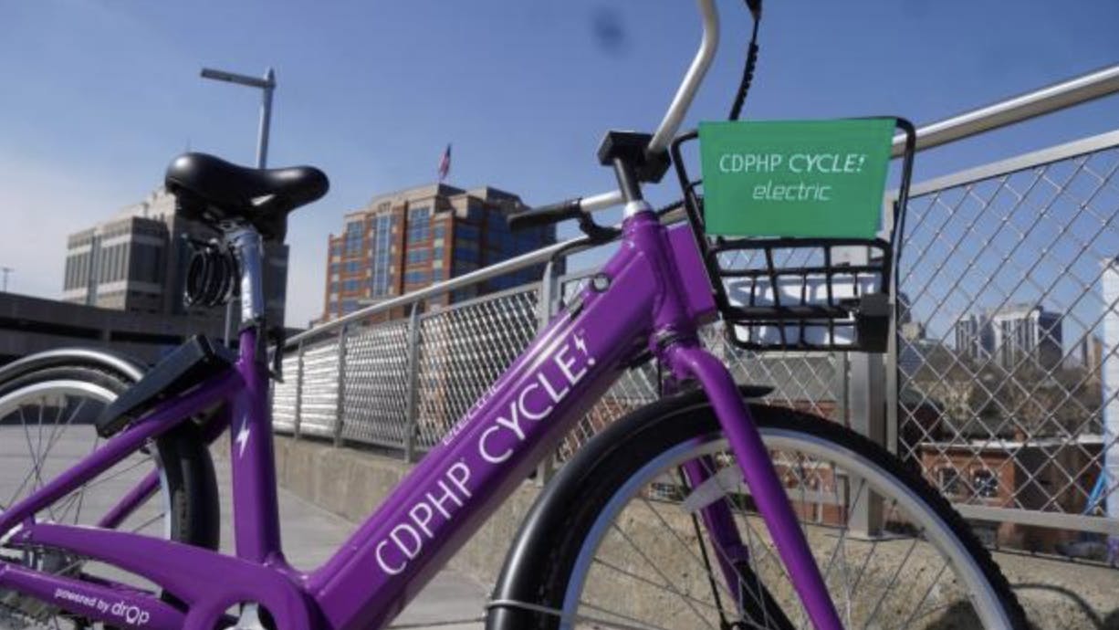a purple CDPHP bikeshare bicycle sits on a sidewalk
