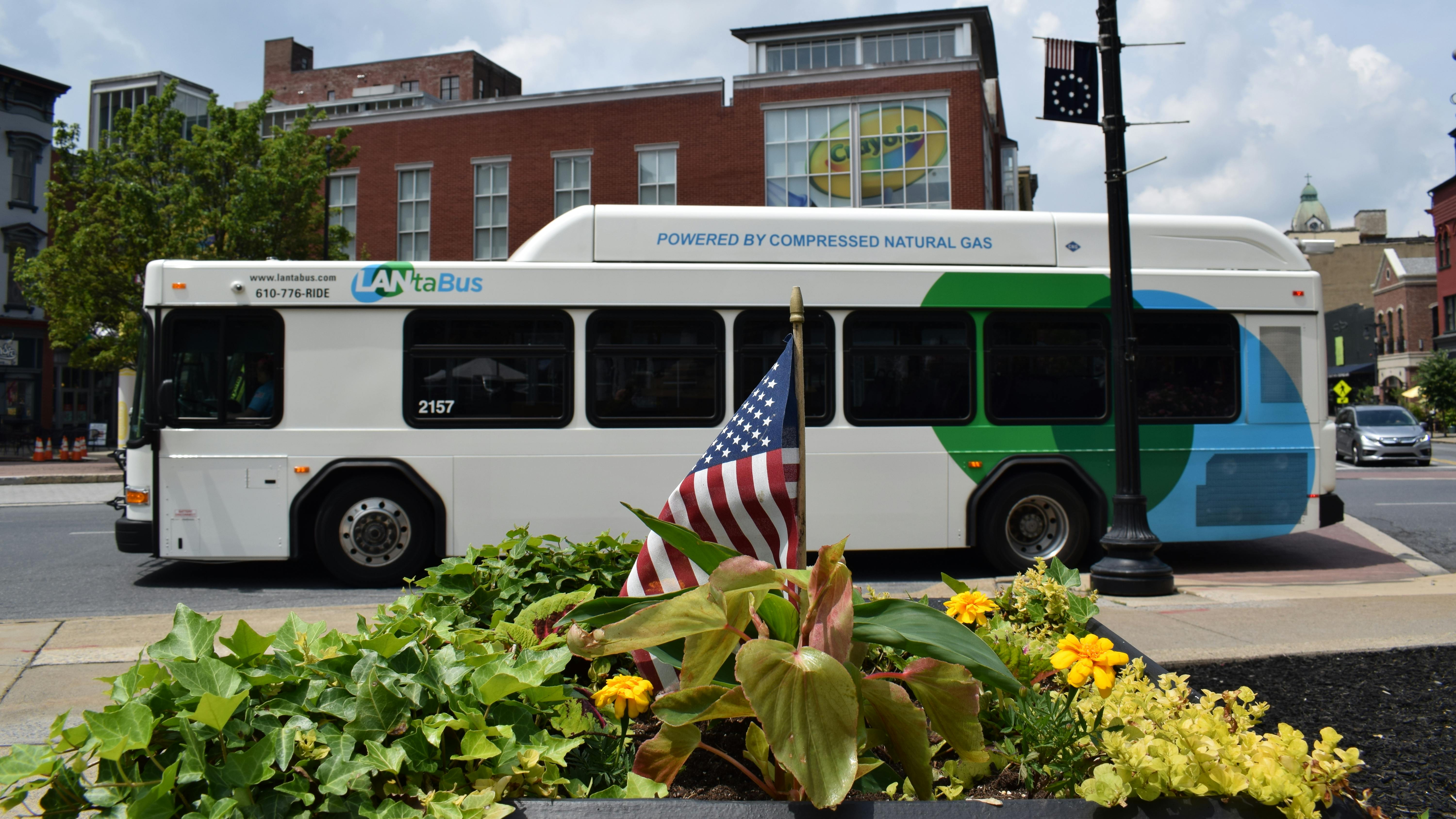 a CNG-powered LANTA-branded bus drives down a town street