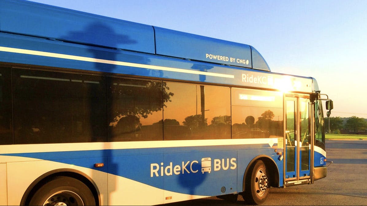 a blue KCATA bus pulls out of a parking lot at sunset
