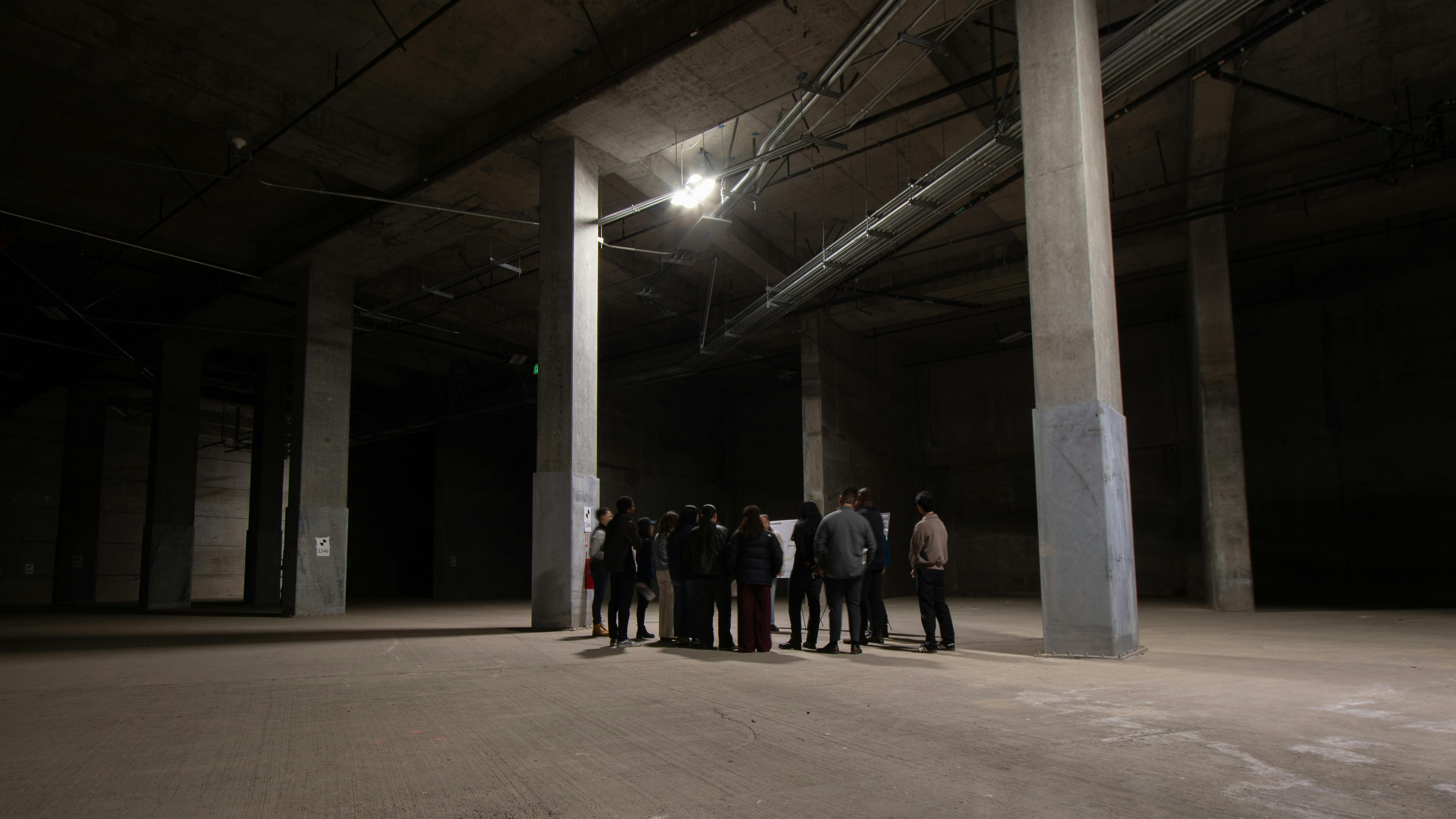 group of students gather around a presentation in the underground The Portal construction site