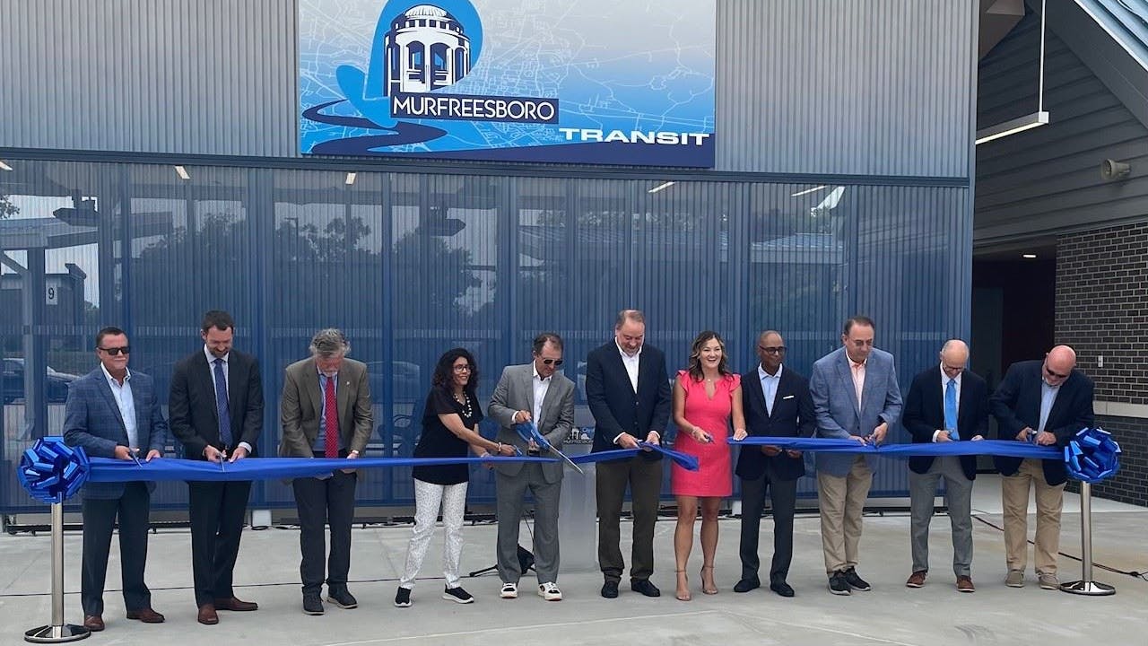 government officials stand before the new transit center, cutting the inaugural ribbon.