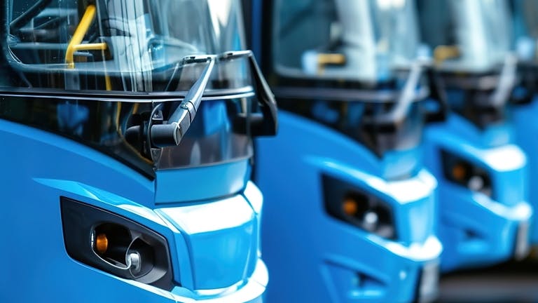 Buses sit in a line next to each other.