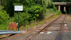 at-grade empty railroad crossing with sign that says no trespassing active railroad next to it at-grade empty railroad crossing with sign that says no trespassing active railroad next to it