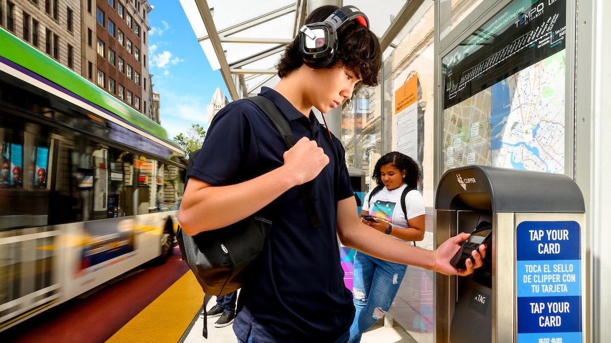 A passenger taps their phone to a Clipper vending machine.