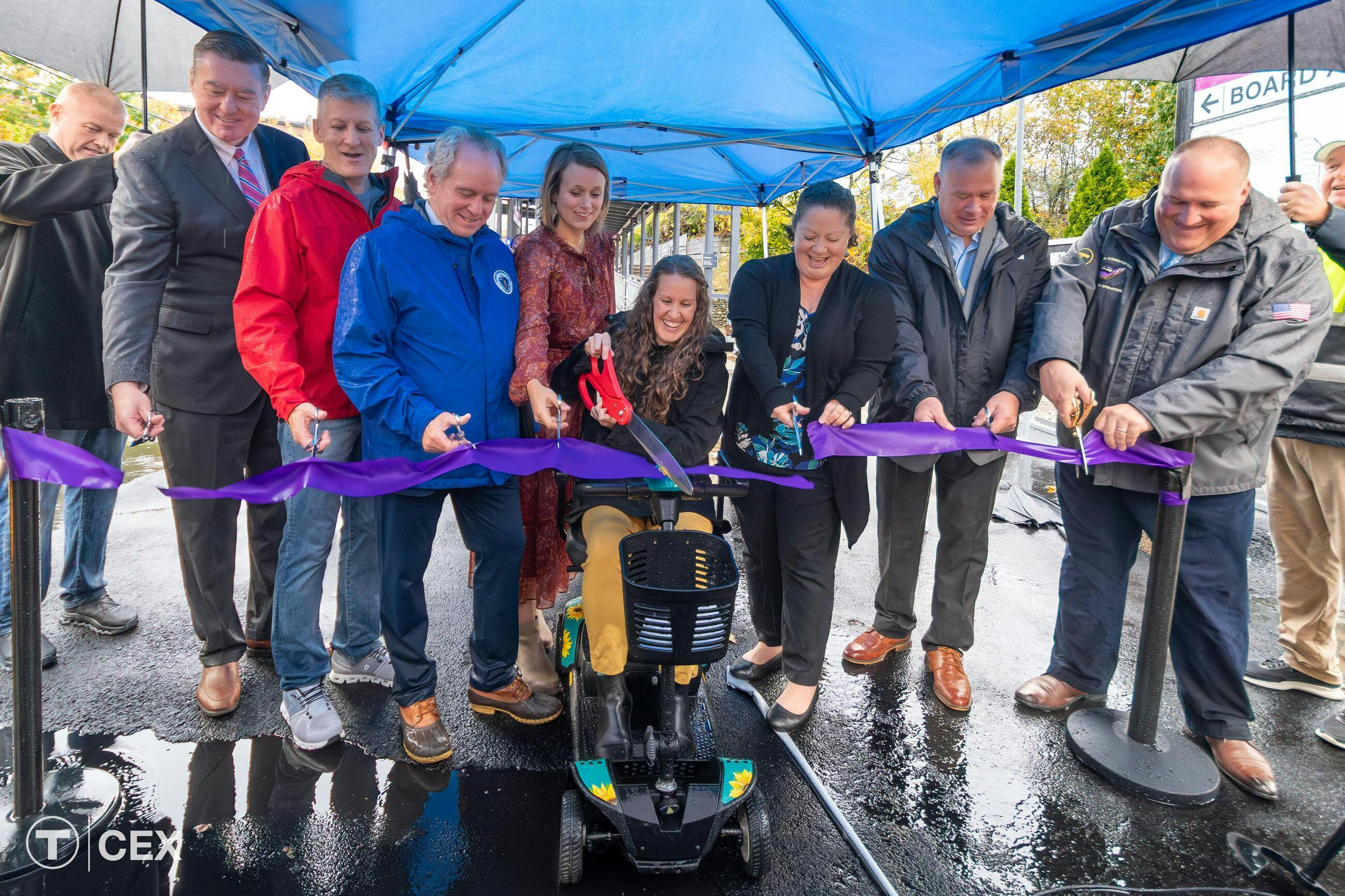 A group of MBTA leadership cuts a ribbon in front of the renovated station.