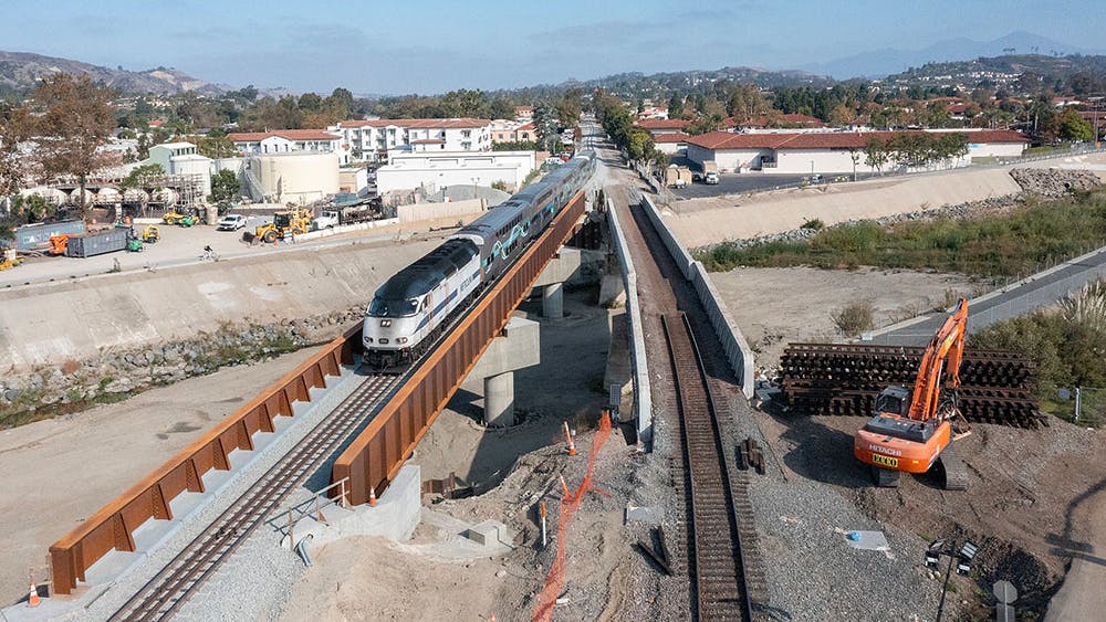 A drone shot of the new and old bridge standing next to each other with a train passing over the new bridge.
